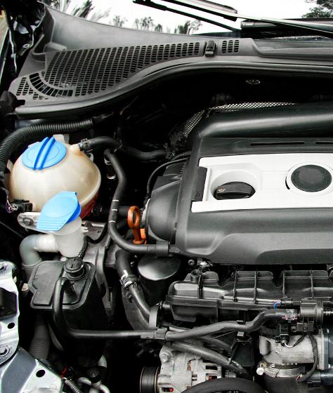 man cleaning car engine with brush wearing gloves in auto repair shop maintaining two components