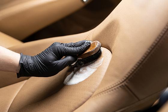 person cleaning a leather car seat with a brush showing attention to detail and care for vehicle maintenance to achieve a pristine finish 2 cleaning tips 2 techniques