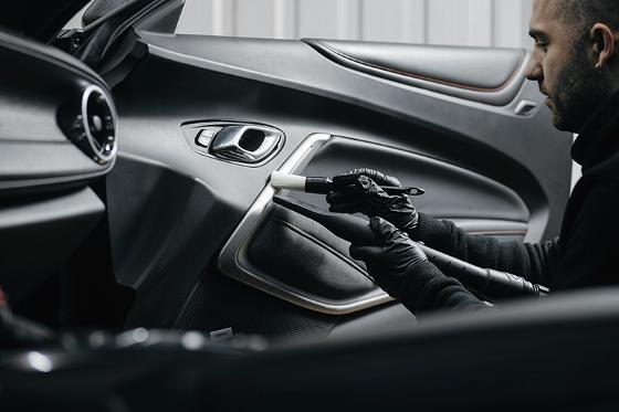 person cleaning the interior of a car focusing on detail and cleanliness representing high quality maintenance techniques for a better driving experience