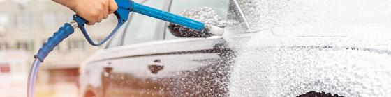 Close-up of a red car being washed with soap and water while a person wearing a yellow glove wipes the surface showcasing its clean shine and detailing techniques creating a sleek appearance related to the number 6 in automotive care.